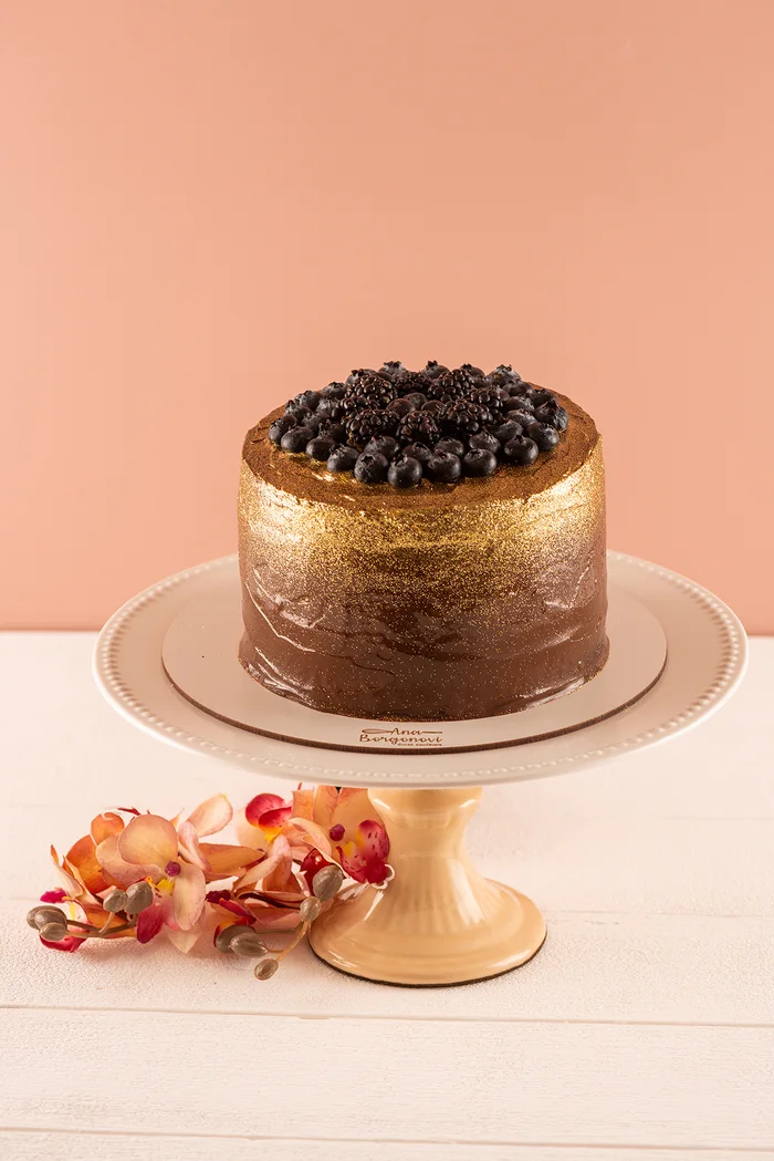 Bolo artesanal de chocolate com frutas vermelhas sobre boleira