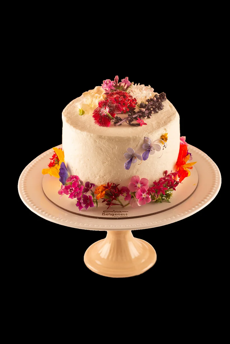 Bolo coberto decorado com flores comestíveis sobre boleira