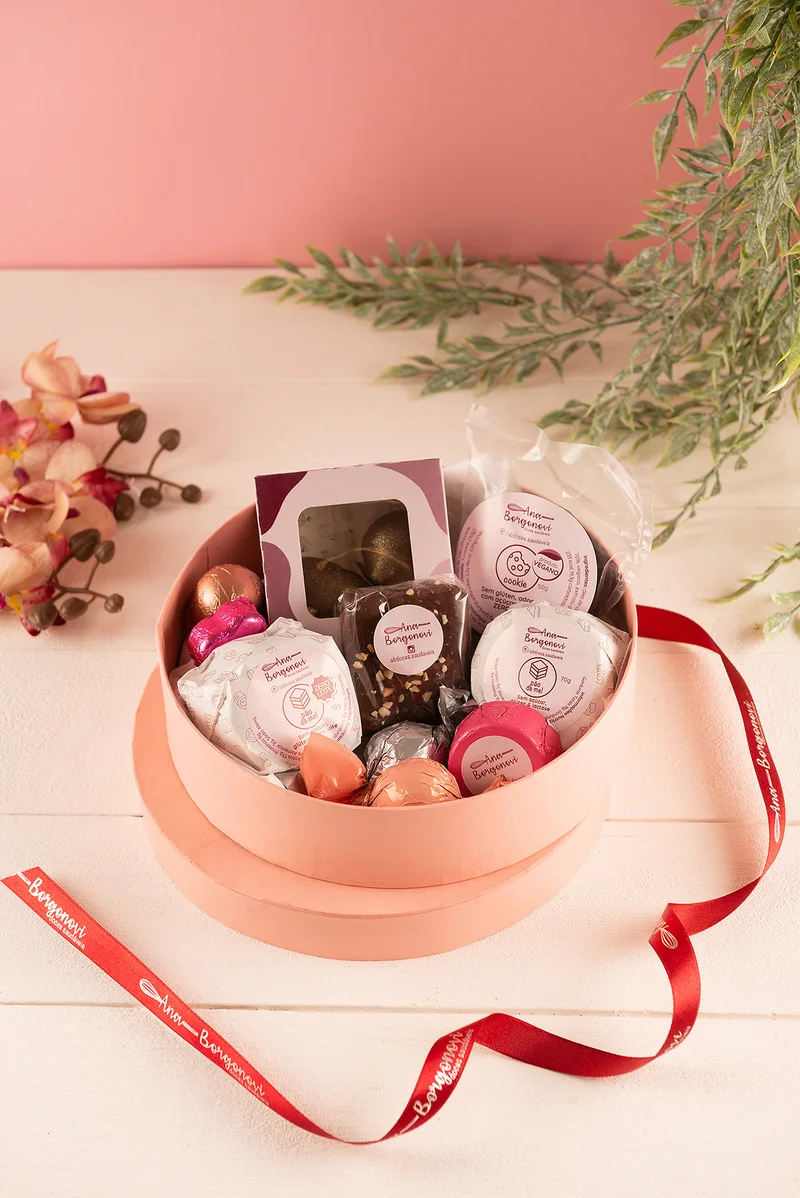 Caixa redonda rosé com doces Ana Borgonovi e fita vermelha