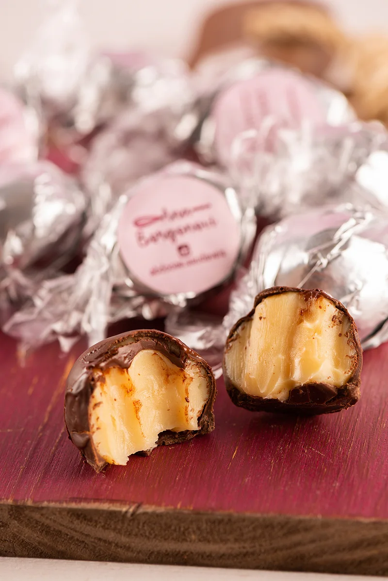 Trufas embaladas em papel metalizado com o selo Ana Borgonovi, uma delas aberta